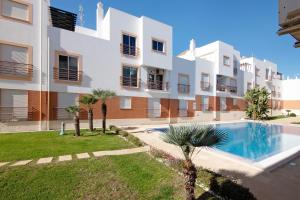 an apartment building with a swimming pool in front of it at Almadrava House in Tavira