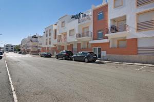 a street with cars parked on the side of a building at Almadrava House in Tavira