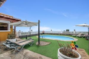 a backyard with a swimming pool and an umbrella at Vv Terrazita in Tijarafe