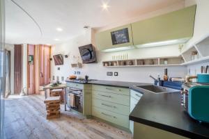 a kitchen with green and white cabinets and a sink at Apartment Belvedere in Caines