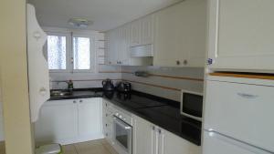 a kitchen with white cabinets and a black counter top at Playa de las Americas Cool Duplex in Playa de las Americas