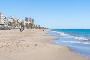 a beach with people walking on the sand and the ocean at Center Beach Calafell in Calafell