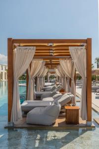 a row of white lounge chairs next to a pool at Venus Hotel in Prishtinë