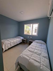 a bedroom with two beds and a window at El Portal Los Álamos in Rincon de los Sauces