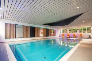 a swimming pool in a house with orange chairs at Fewo Brünnstein - Nr 46 Pool, Sauna in Oberaudorf