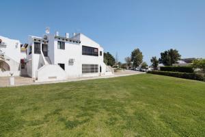 a white house with a green lawn in front of it at Pedras Del Rei 26 in São Pedro