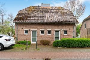 a brick house with a car parked in front of it at Nordseezeit Strandnah u Poolrabatt in Butjadingen