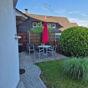 a patio with a table and chairs and a red umbrella at Ferienwohnung Kleine Pause in Emmendingen
