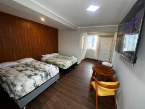 a room with two beds and a table and a chair at Hotel Atenas in Barranca