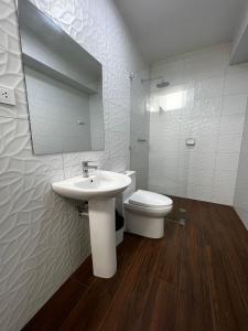 a bathroom with a sink and a toilet and a mirror at Hotel Atenas in Barranca