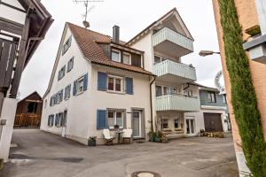 a large white house with blue shuttered windows at Schmid am See in Gaienhofen