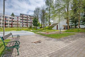 a green park bench sitting on a brick walk at Ferienappartement Waldgenuss in Sankt Englmar