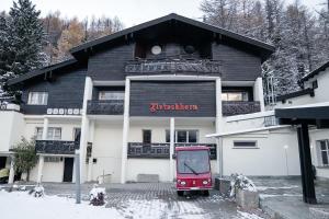 a red train is parked in front of a building at Waldhotel Fletschhorn Private Whole Hotel in Saas-Fee 360 Alpine Views & Sauna in Saas-Fee
