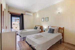 two beds in a small room with a window at Casa Enxame in Armação de Pêra