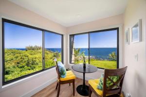 a room with a table and chairs and large windows at Sealodge A2 Romantic Ocean View Oasis with Pool in Princeville