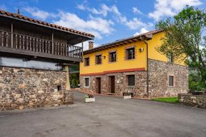 a yellow house with a stone wall at Pedregal in Gijón