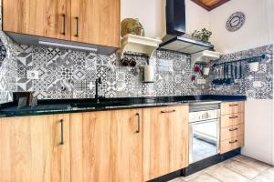 a kitchen with wooden cabinets and black and white tiles at Tío Salvador in Bolbaite