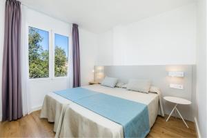 a white bedroom with a large bed and a window at Apartament Massanet 2c in Canyamel