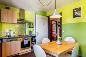 a kitchen with green walls and a wooden table and chairs at Blackforest Ferienwohnung in Sankt Georgen im Schwarzwald