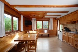 a kitchen with a wooden table and some windows at Ferienhaus Villa Kanisblick in Bizau