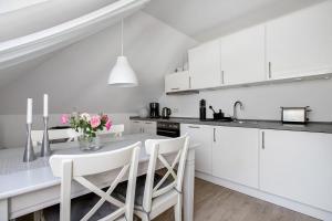 a kitchen with white cabinets and a table with pink flowers at Ferienwohnung Marita Carstensen in Viöl