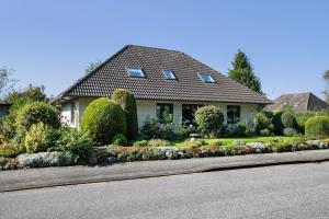 a house with bushes and flowers in front of a street at Ferienwohnung Marita Carstensen in Viöl