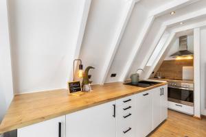 a kitchen with white cabinets and a wooden counter top at Nurdachhaus Sauerland in Kirchhundem +19 photos