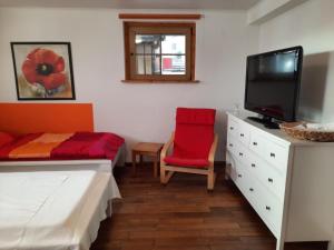 a bedroom with a bed and a tv and a red chair at Ferienwohnung Dörflich in Meinerzhagen