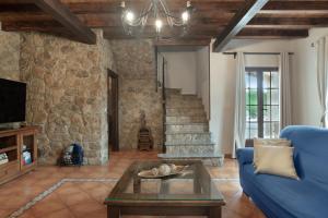 a living room with a blue couch and a stone wall at Villa los mellizos in Arriate