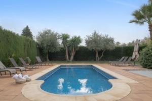 a swimming pool in a yard with chairs and trees at Villa los mellizos in Arriate