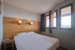 a bedroom with a white bed and two windows at appartement duplex in LʼHuez