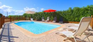 a swimming pool with chairs and a red umbrella at Can Olivaret in Campos