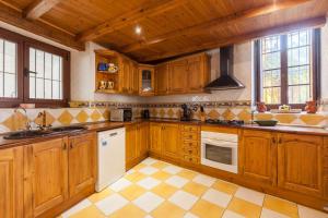 a large kitchen with wooden cabinets and white appliances at Masía Can Trabal in Olerdola