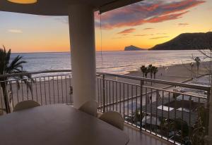 a balcony with a table and a view of the beach at Front Line on the beach in Calpe
