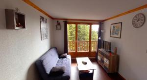a living room with a couch and a clock on the wall at Appartement Le Maevan in Vassivière