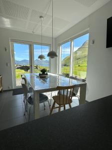 a dining room with a table and chairs and mountains at Luxury Cottage with Stunning Views - Okkara summarhús við Gjógv in Við Gjógv