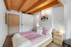 a bedroom with a bed with pink and white sheets at Ciasa Irene App Mansarde in La Villa