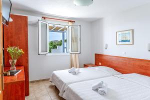 a bedroom with two beds and a window at Anemologio 302 Tinos in Agios Ioannis