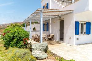 a white house with blue shutters and a patio at Anemologio 302 Tinos in Agios Ioannis