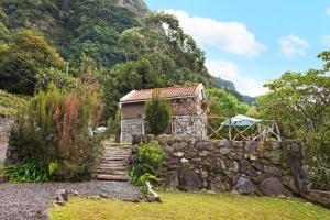 a house in the mountains with a stone wall at The Perfect Cottage in São Vicente