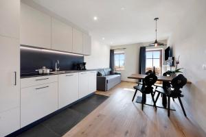 a kitchen with white cabinets and a table and chairs at Leierhof Wicky in Rodengo