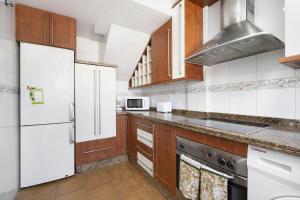 a kitchen with white appliances and wooden cabinets at Casa Costa Ballena Dahlia in Costa Ballena