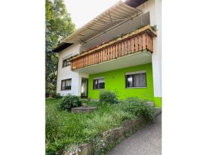 a green and white house with a wooden balcony at Ferienwohnung Josefa Ganter 80qm in Ühlingen-Birkendorf