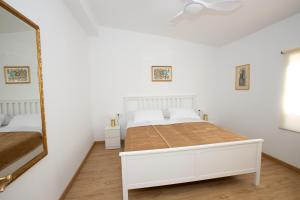 a white bedroom with a bed and a mirror at La Casita in San Vicente del Raspeig +20 photos