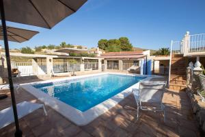 a swimming pool with two chairs and an umbrella at La Casita in San Vicente del Raspeig