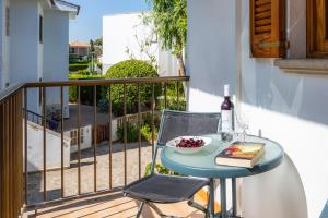 a table with a bottle of wine and a bowl of fruit on a balcony at Es Pujol in Alcudia