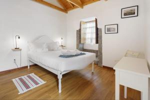 a white bedroom with a white bed and a window at Adega Peróla in Cais do Galego