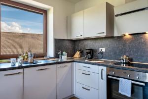 a kitchen with white cabinets and a large window at Gatscherhof Apt Abendrot in Luson +22 photos