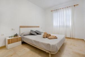 a white bedroom with a bed with two pillows at Casa Yeray in Caleta De Fuste +17 photos