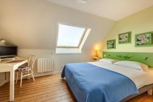 a bedroom with a bed and a desk and a window at La Demeure Océane in Portsall